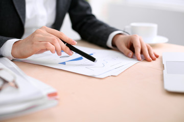 Business woman sitting at the table and examines the financial results