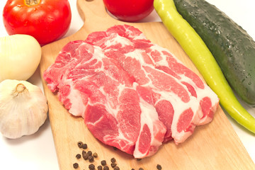 Pork neck chop meat with raw vegetables on cutting board