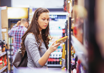 Young couple buying groceries together in supermarket. Focus on woman