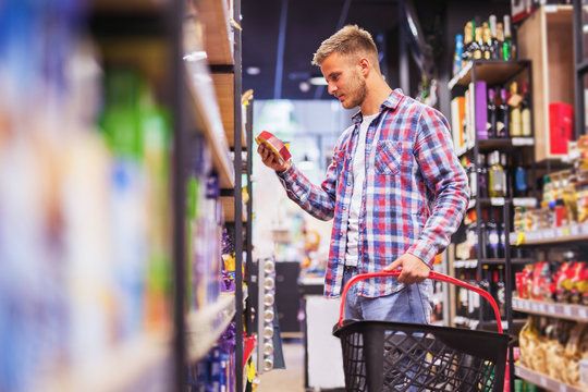 Young man shopping in a supermarket holding shopping cart