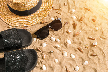 Fototapeta na wymiar Summer beachwear, flip flops, hat, sunglasses and seashells on sand beach.