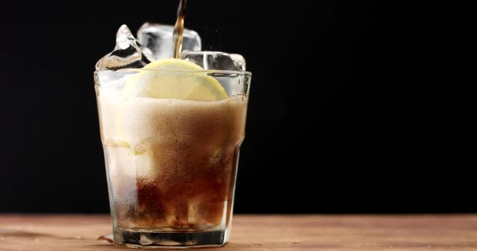 glass with ice cubes and lemon slide and cola. rom cola, fresh drink, ice cubes and bubbles