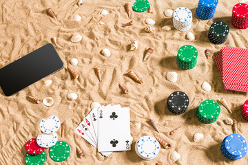 Online poker game on the beach with digital smart and stacks of chips. Top view