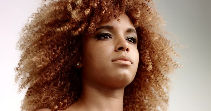 closeup portrait of black woman with beauty curly blondie hair moves by wind