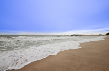 Fototapeta na wymiar Beach with stone wall and blue sky.