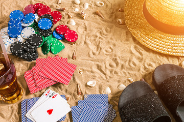 Beachpoker. Chips and cards on the sand. Around the seashells, hat and flip flops. Top view