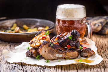 Grill pork ribs  Juicy roasted pork ribs with draft beer on rustic oak table.