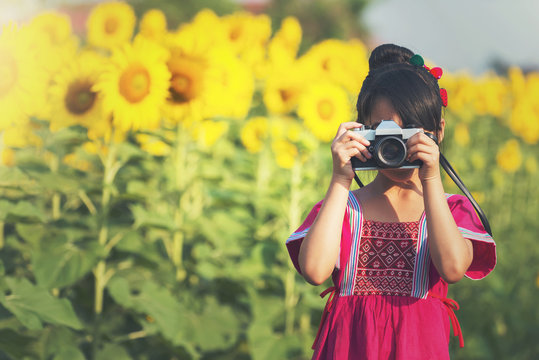 Portrait of cheerful smiling little girl making photo with camera in hands outdoors