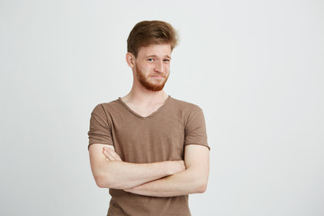 Portrait of young handsome man with beard looking at camera with contempt crossed arms over white background.