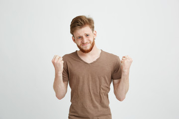 Portrait of nervous young handsome man hoping praying looking at camera over white background.