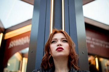 Portrait of a beautiful redhead. Fiery hair and full lips. Walking around the city