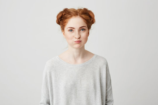 Portrait of young pretty ginger girl making funny face looking at camera over white background.