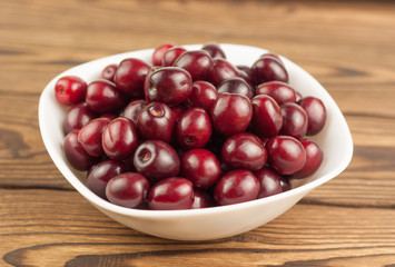 Red fresh cherries in bowl on old wooden background
