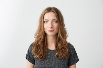 Portrait of young pretty cheerful girl smiling looking at camera over white background.