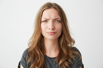 Portrait of displeased young pretty girl looking at camera with contempt over white background.