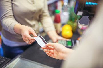 Woman paying with a credit card in a supermarket closeup
