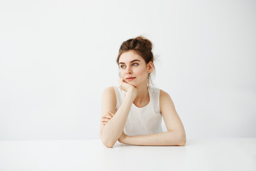 Fototapeta premium Dreamy young beautiful girl student sitting at table dreaming thinking over white background.