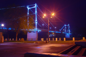 Naklejka na ściany i meble Pedestrian bridge over the Ural River / Photo taken in Russia, in the city of Orenburg, at night
