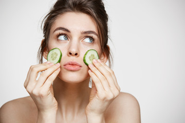 Young beautiful girl with perfect clean skin holding cucumber slices over white background. Beauty cosmetology and spa.