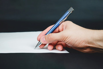 Person sign document and hand holds blue pen on dark background