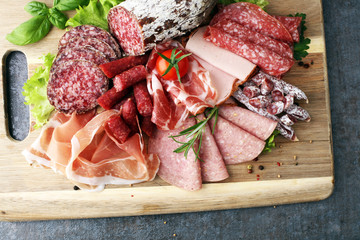 Food tray with delicious salami, pieces of sliced ham, sausage, tomatoes, salad and vegetable - Meat platter with selection