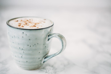 Cappuccino in a rustic style mug on a marble table
