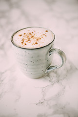 Cappuccino in a rustic style mug on a marble table