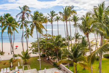 Fototapeta premium Beautiful beach view. Amazing ocean blue water with an island to water through palms at Caribbean sea.