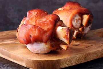 Smoked ham hock with herbs and spices on wooden plate.