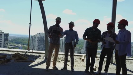 Aerial Shot Of Builders Team On Construction Site Discussing Plan Of Project With Architect And Contractor Using Blueprint On Digital Tablet - Powered by Adobe
