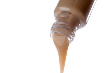 Cosmetic liquid pouring from bottle isolated on white background