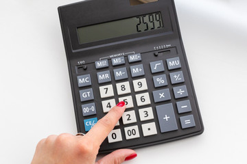 hand with the calculator on the desktop, close up