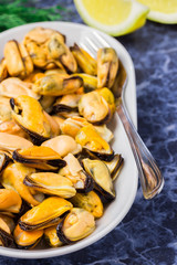 Mussels in a white plate on marble background. Healthy seafood.