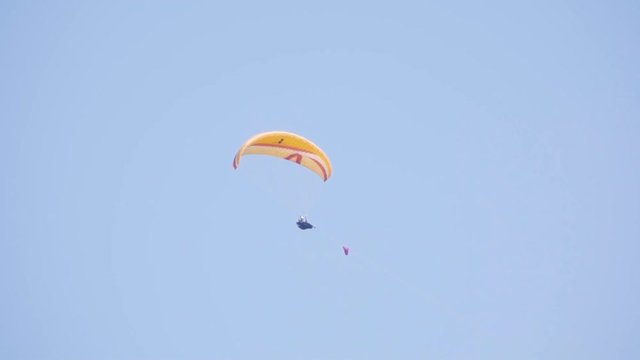 man is flying on a paraglider against the blue sky.