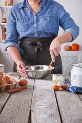 Woman baker stir dough with eggs, butter and flour