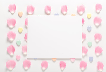 Rose petals and blank white message card aligned on a white background