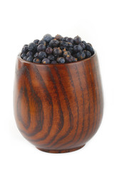 juniper berries  in wooden cup isolated