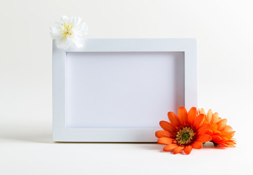 Blank white picture frame with flowers on a white background