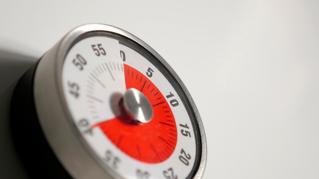 Classical vintage kitchen countdown timer close up shot with analog clock face and red remaining time display, 40 minutes left, low depth-of-field with blur