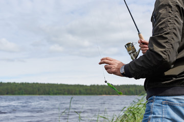 Man fishing bass with spinning rod in a lake.
