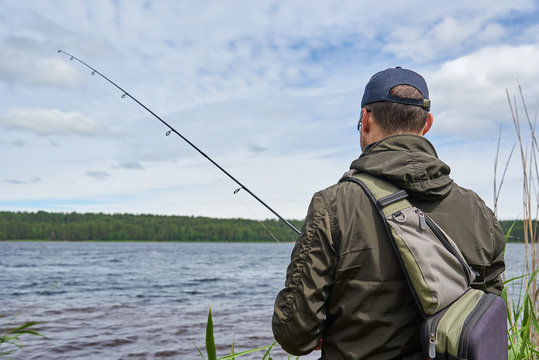 Man fishing with spinning rod in a lake.
