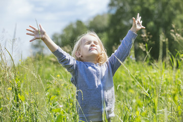 Naklejka na ściany i meble Little beautiful baby girl outdoors in a field in the fresh air happy