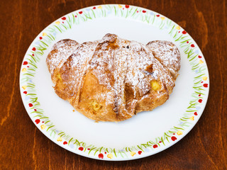 fresh croissant filled by vanilla cream on table