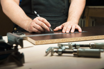 Male hands draw a pencil on the ruler