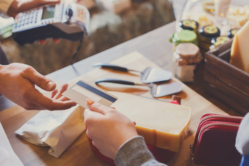 Customer paying for order of cheese in grocery shop.