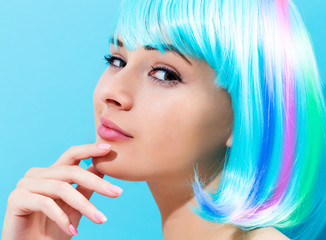 Beautiful woman in a bright blue wig on a blue background