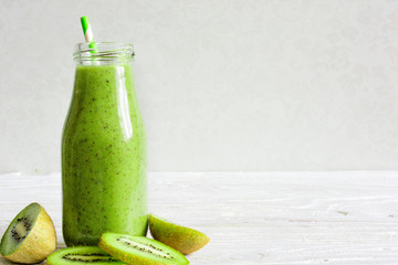 bottle of green smoothie with fresh kiwi and banana fruits and berries