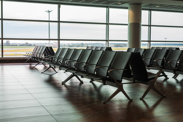 Empty airport terminal waiting area with chairs.