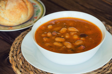 Bean soup with the buns on a  wooden table.