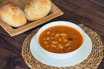 Bean soup with the buns on a  wooden table.